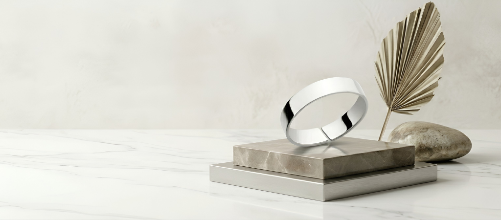 Silver ring on a metallic stand with a palm leaf and stone on a light background